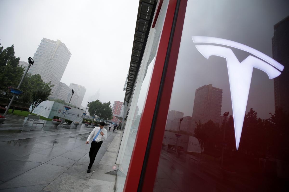 A man walks near a logo of Tesla outside its China headquarters at China Central Mall in Beijing, China July 11, 2018. REUTERS/Jason Lee