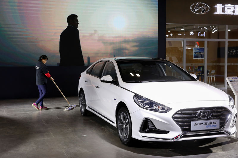 A worker cleans the ifloor next to a Sonata hybrid at a booth of Beijing Hyundai Motor, the joint venture between South Korea's Hyundai Motor and China's BAIC Motor, during an energy-savng and new energy vehicles expo in Beijing, China October 18, 2018. Picture taken October 18, 2018.  REUTERS/Thomas Peter
