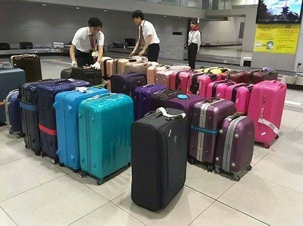 The airport staff sorts the luggage by color before putting it on the belt