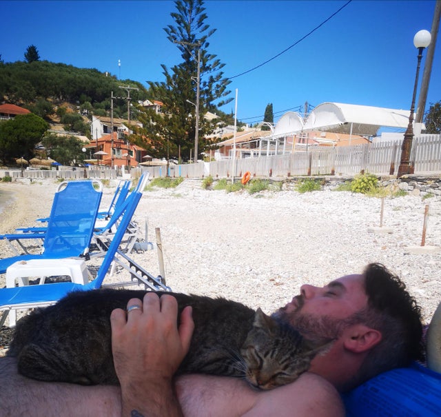 Husband and the local beach cat, sunbathing in the Corfu sun